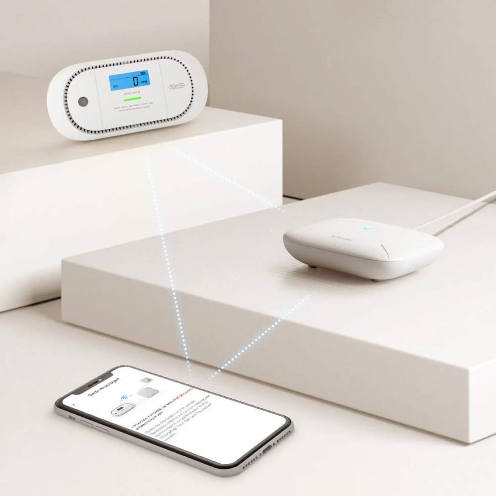 Ein weißer CO2-Detektor, ein Router und ein Smartphone verbunden auf Stufen.