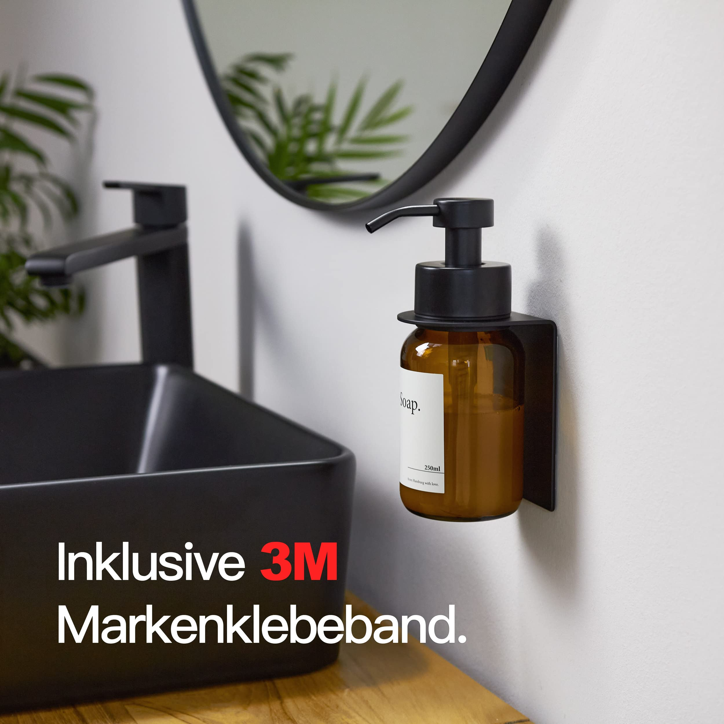 Bernsteinfarbener Seifenspender mit schwarzer Halterung an einer Wand neben einem schwarzen Waschbecken.