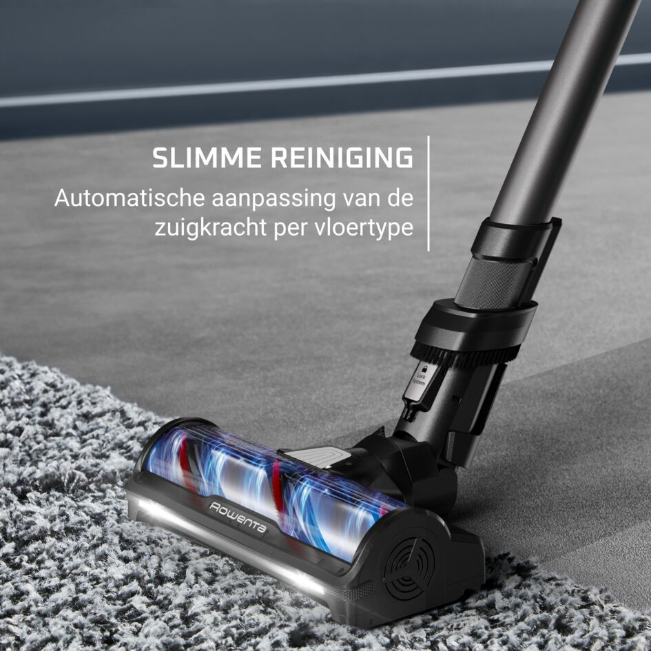 Testina dell'aspirapolvere con luci LED su tappeto grigio e pavimento in legno.