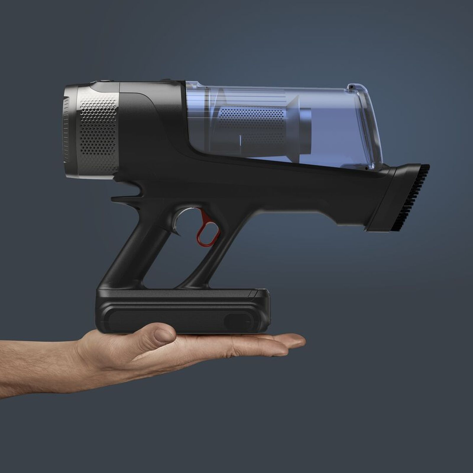 Una mano sostiene un elegante aspirapolvere portatile nero con contenitore trasparente su sfondo grigio.
