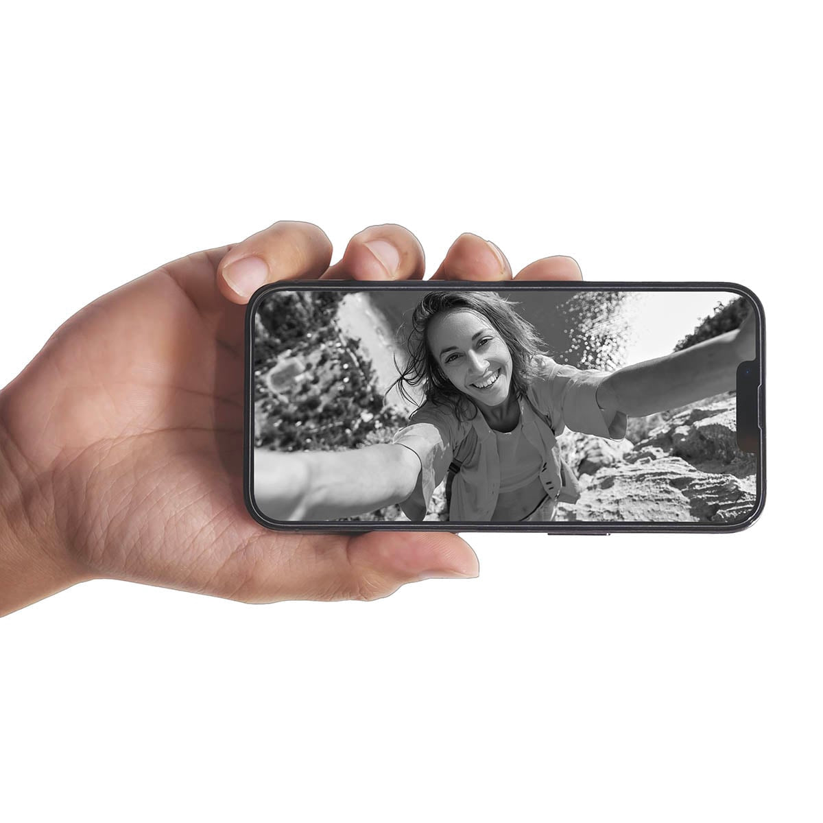 Eine Hand hält ein Smartphone mit einem schwarz-weißen Selfie einer lächelnden Frau im Freien.