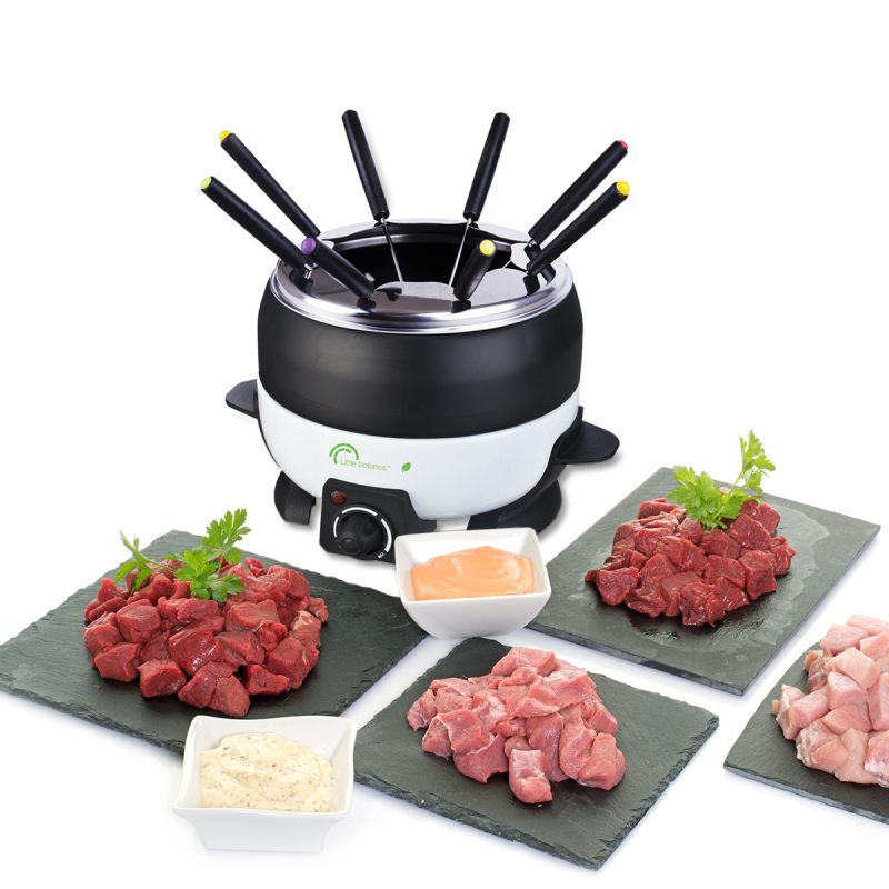 Ein schwarzer und weißer Fondue-Topf surrounded by slate plates with cubed meat and bowls of sauce on a white background.