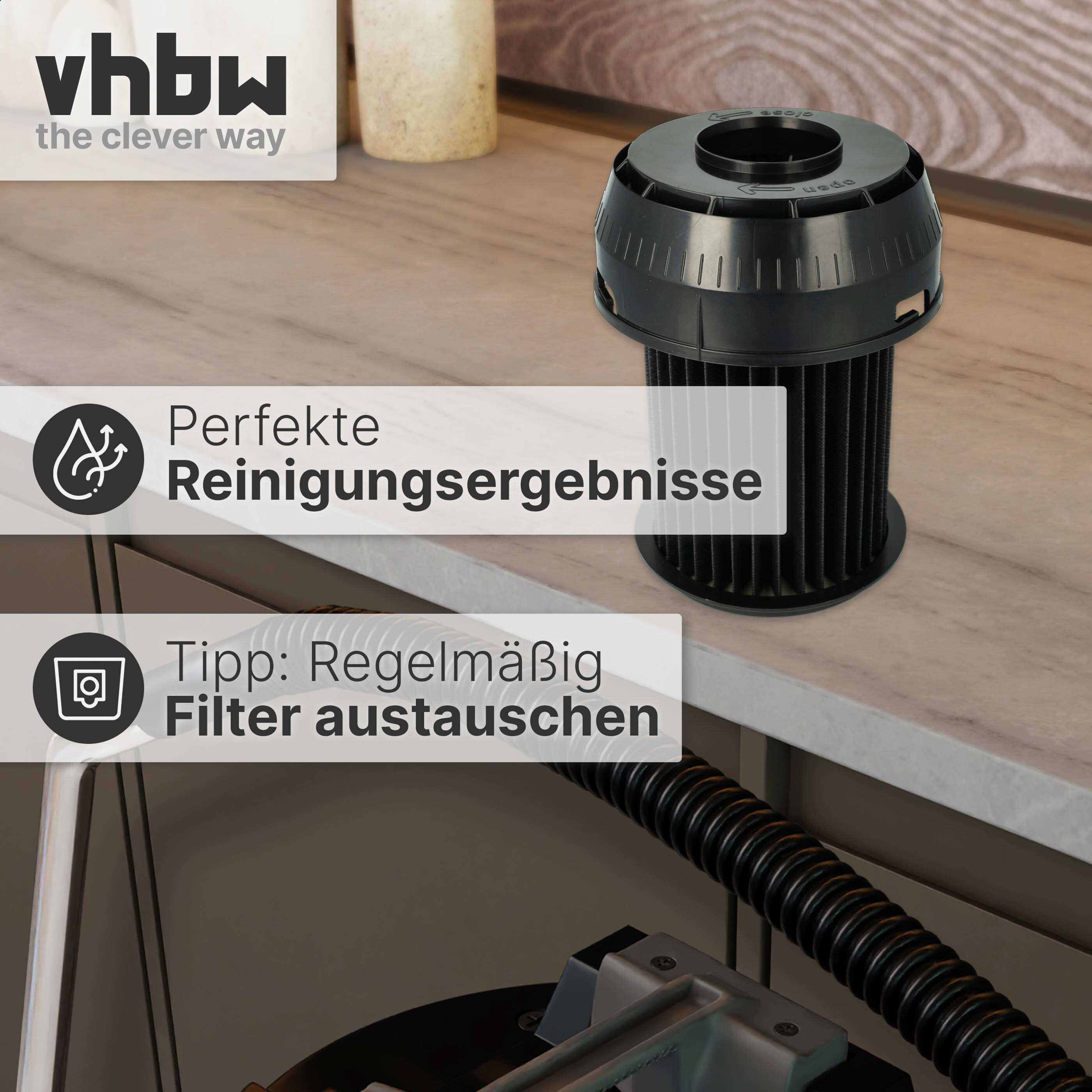 Ein schwarzer zylindrischer Staubsaugerfilter liegt auf einer Holzarbeitsplatte neben einem Staubsaugerschlauch.