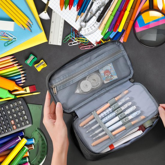 Geöffnete Federmappe mit Stiften und anderem Schulbedarf auf dunklem Tisch.