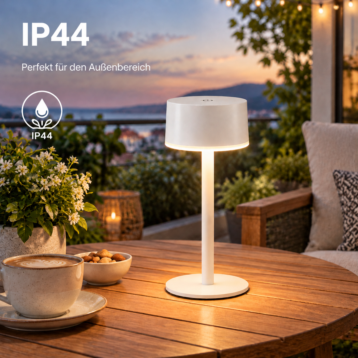 Eine weiße IP44 Tischleuchte steht auf einem Holztisch auf einem Balkon im Sonnenuntergang.