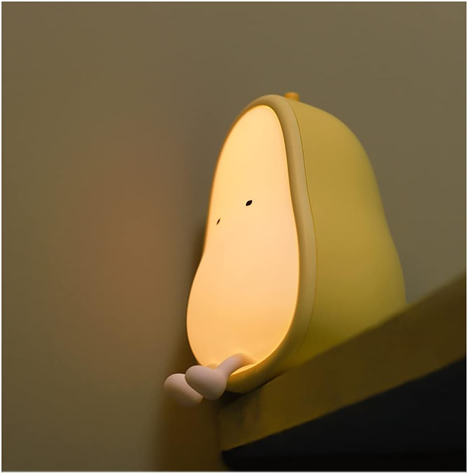 Eine gelbe, birnenförmige Lampe mit kleinen Beinen sitzt auf einem Regal gegen eine Wand.