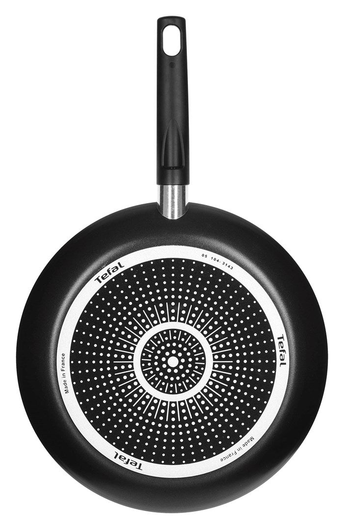 Spód czarnej patelni Tefal z okrągłą wzorzystą podstawą indukcyjną i długim uchwytem.