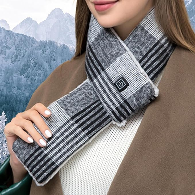 Eine Frau trägt einen schwarz-weiß karierten beheizbaren Schal mit Ein-Knopf, Mantel und schneebedecktem Berg.