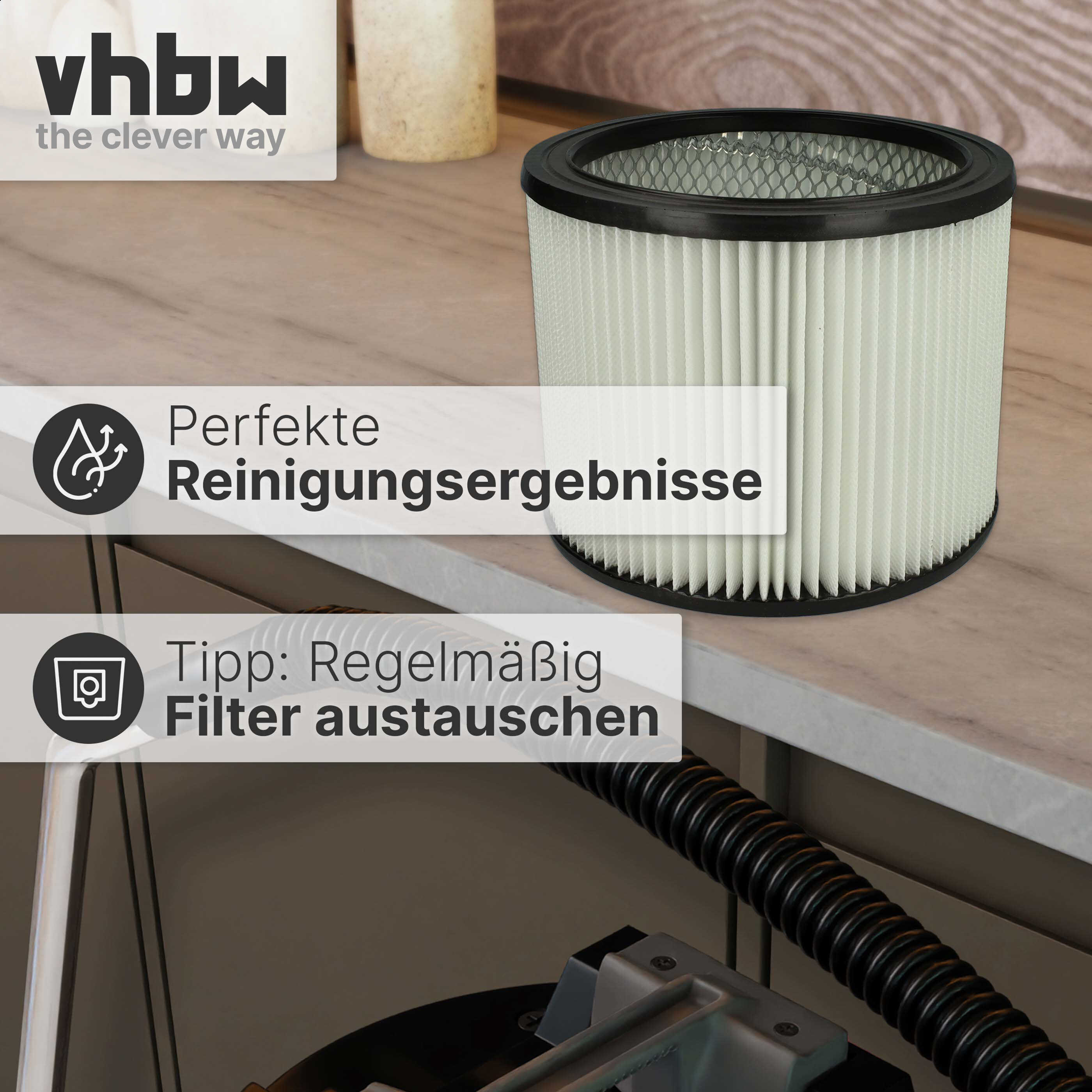 Ein zylindrischer Staubsaugerfilter auf einer Holzarbeitsplatte neben einer schwarzen Schlauchverbindung.