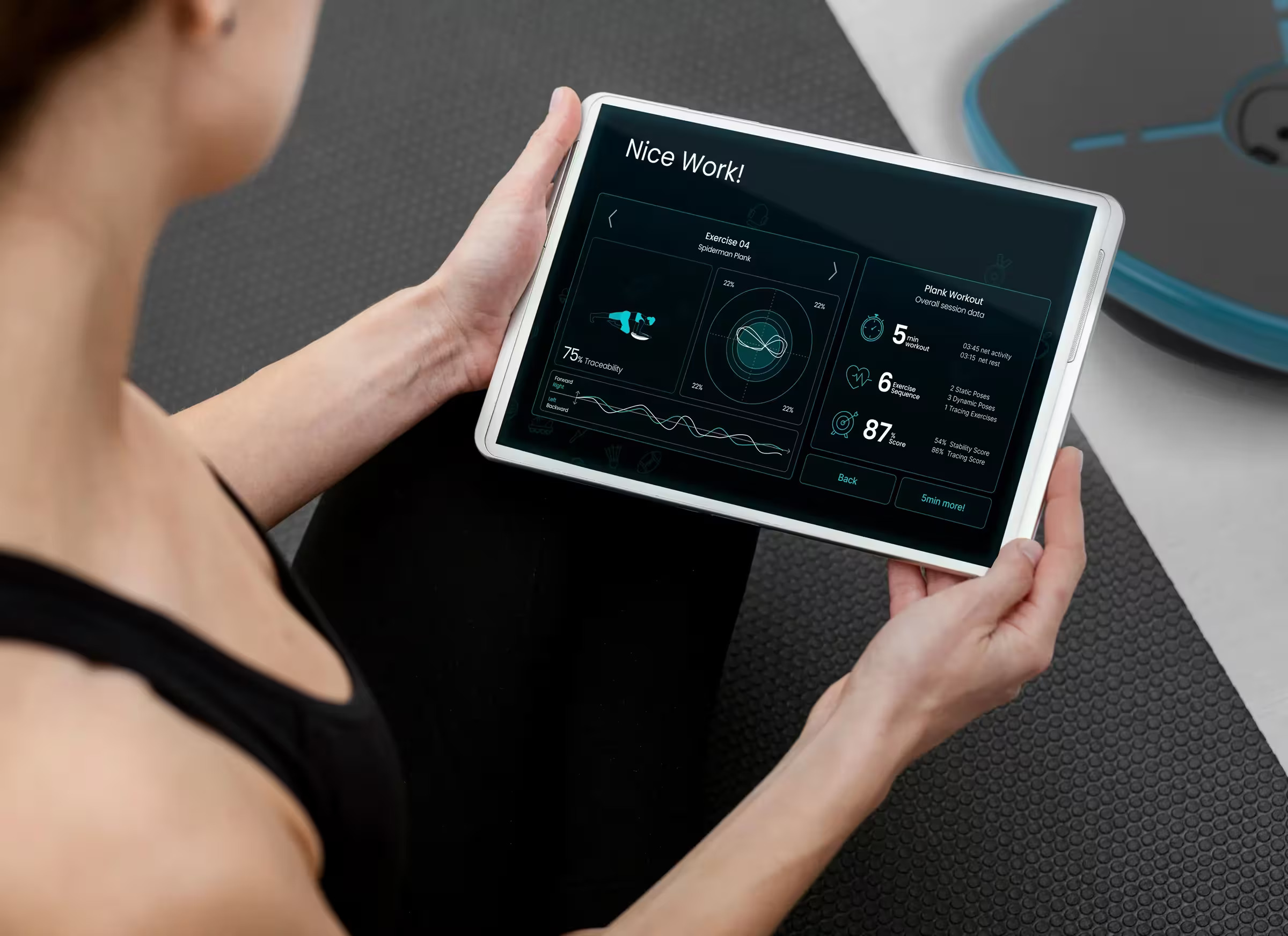 Una donna tiene un tablet con un'app di fitness su un tappetino.