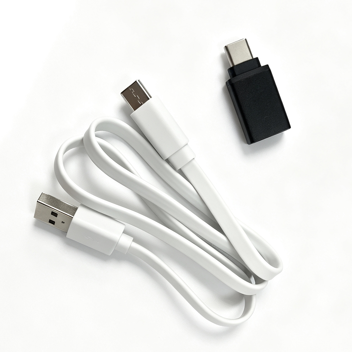 Ein zusammengerolltes weißes USB-Kabel und ein schwarzer USB-C-Adapter liegen auf einer weißen Oberfläche.