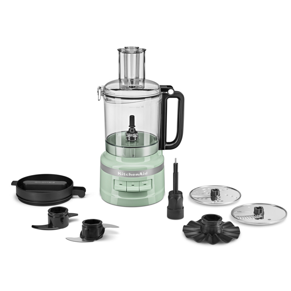 Beyaz arka planda bıçaklar ve diskler gibi aksesuarlarla birlikte yeşil KitchenAid mutfak robotu.