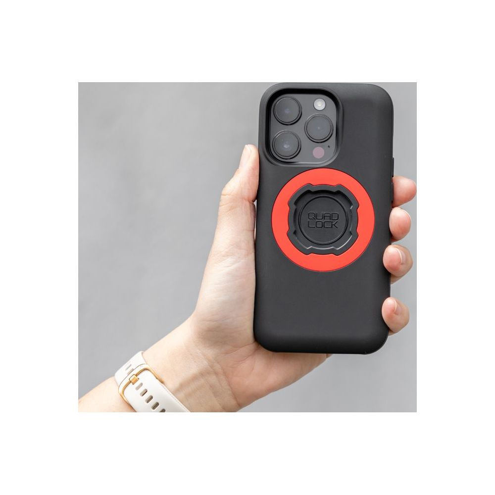 Eine Hand hält ein schwarzes Smartphone mit einer roten Quad Lock Halterung auf der Rückseite.