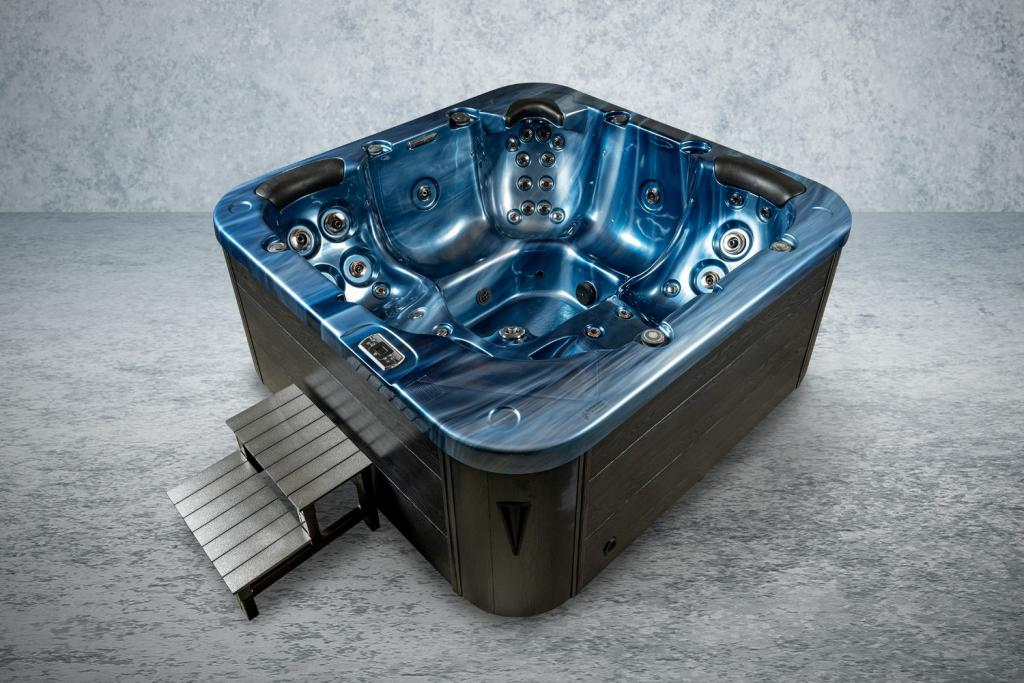 Ein blauer Whirlpool mit Holzverkleidung und Treppe steht auf einem grauen Steinboden.