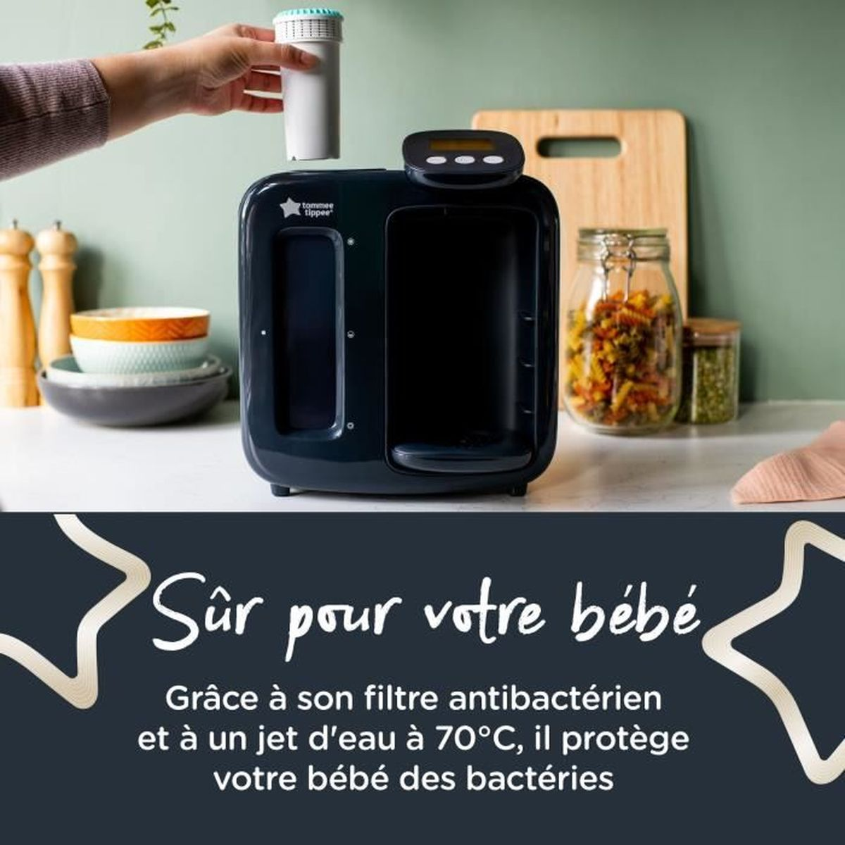 Hand platziert einen Filter in ein schwarzes Tommee Tippee Gerät auf einer Küchentheke mit Lebensmitteln im Hintergrund.