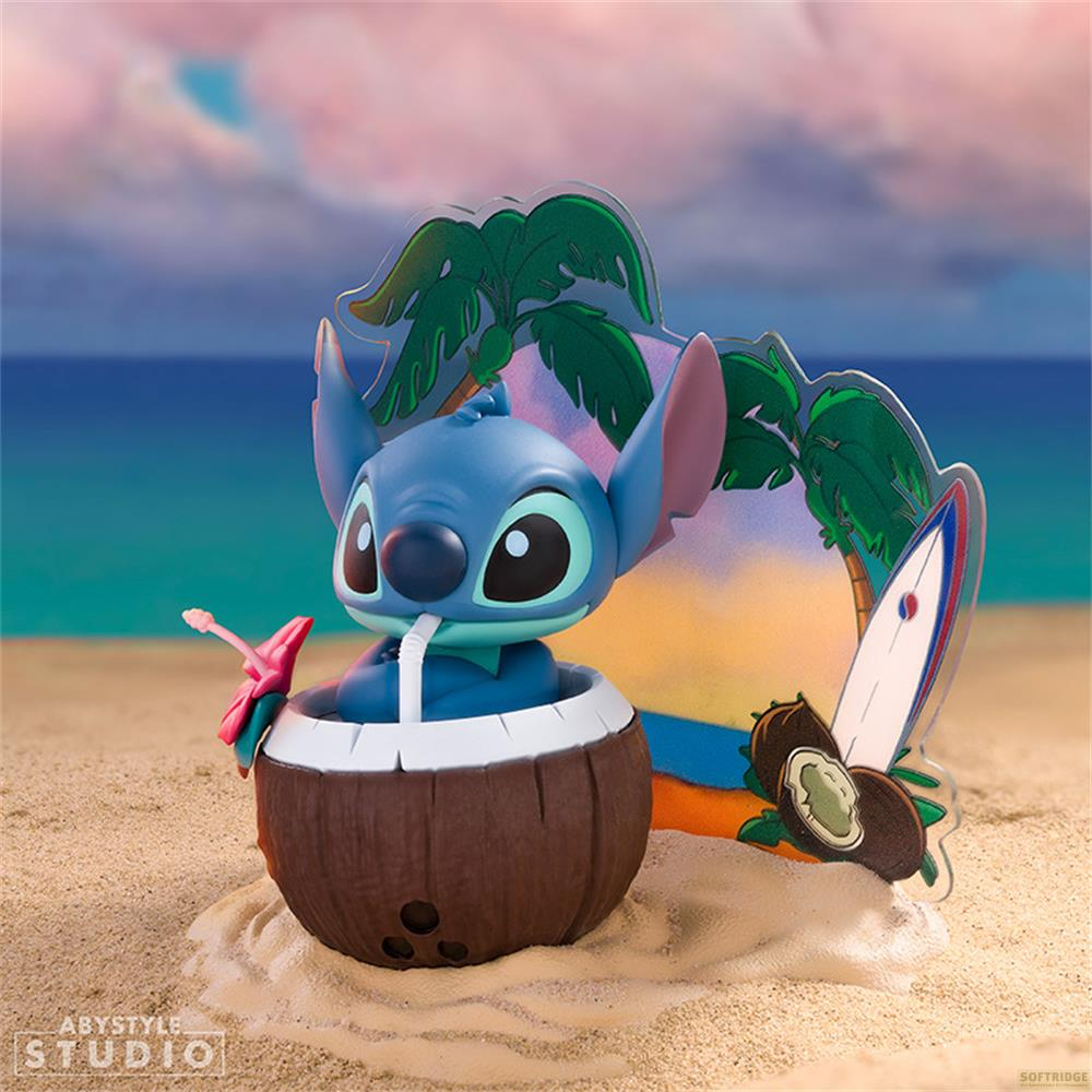 Stitch sitzt in einer Kokosnuss mit Strohhalm am Strand, dahinter Palme und Surfbrett.