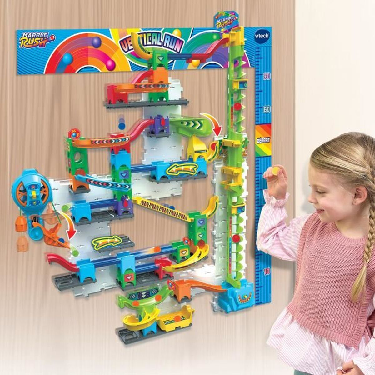 Ein blondes Mädchen in einem rosa Pullover spielt lächelnd mit einer bunten VTech Marble Rush Kugelbahn.