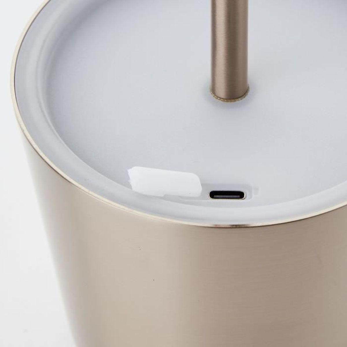 Nahaufnahme der Unterseite einer goldfarbenen Lampe mit einem USB-C-Anschluss und einer weißen Abdeckung.