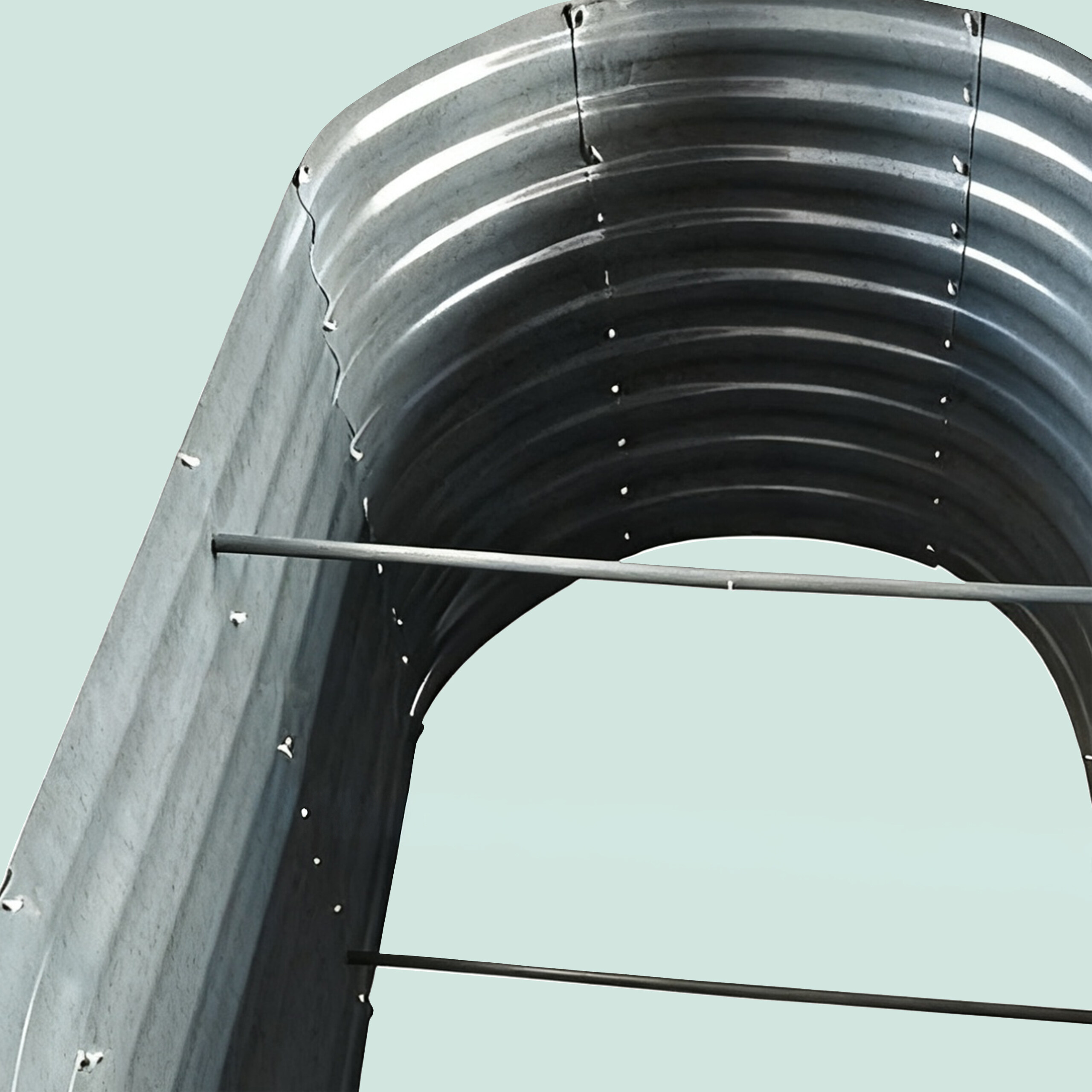 Ein gewölbtes Metallblech mit horizontalen Verstrebungen vor hellblauem Hintergrund.