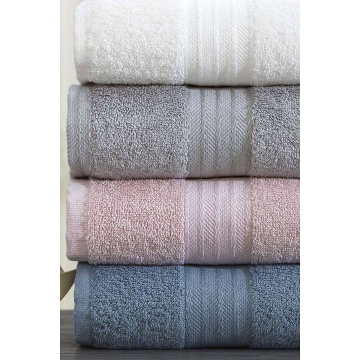 Ein Stack aus vier weichen Handtüchern in Weiß, Grau, Rosa und Blau.