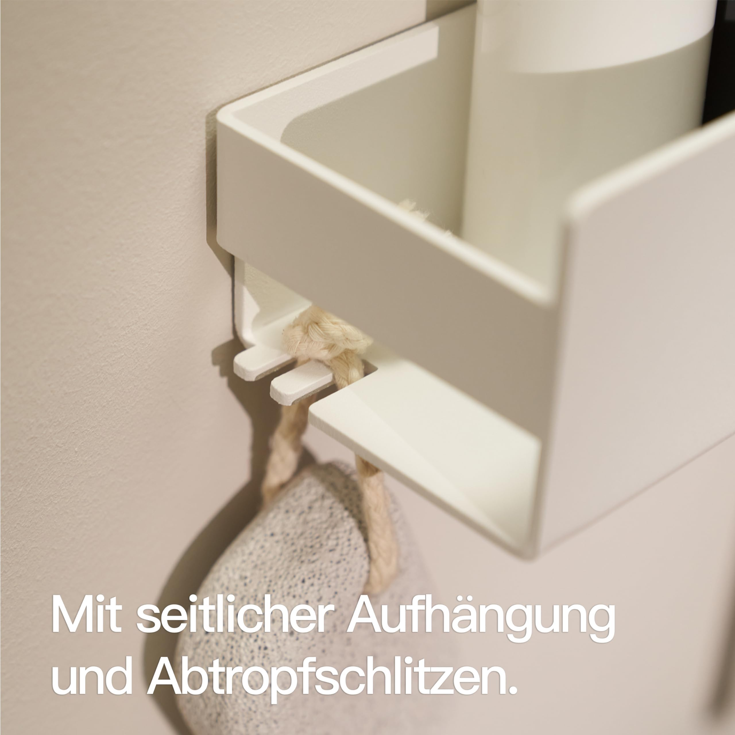 Weiße Wandhalterung mit Aufhängung und Abtropfschlitzen, daran hängt ein Bimsstein.