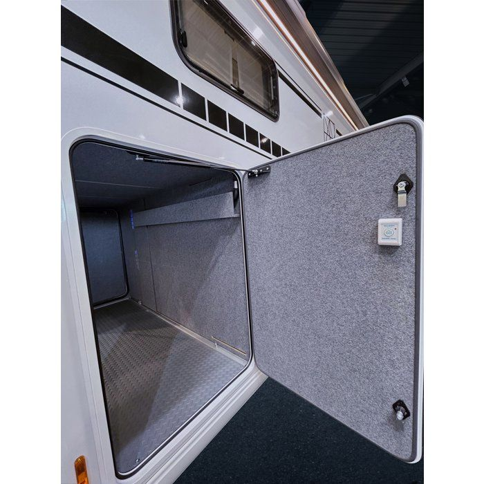 Ein offenes Staufach eines weißen Wohnmobils mit grauem Teppichinnenraum und Metallboden.