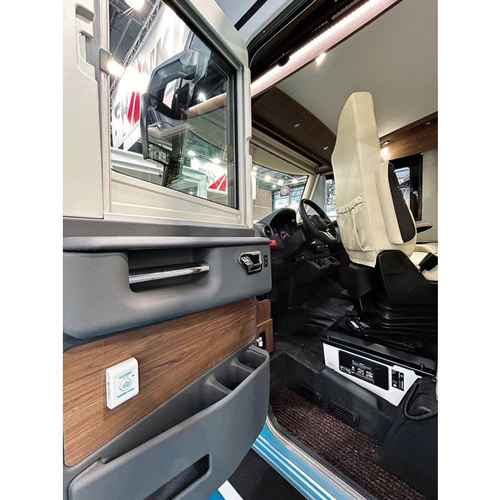Geöffnete Tür eines modernen Wohnmobi lfahrersitzes mit Holzverkleidung und Becherhalter.