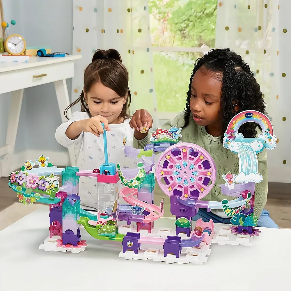 Zwei Mädchen spielen zusammen an einem bunten Murmelbahn-Spielset mit einer integrierten rosa Riesenrad-Attraktion.