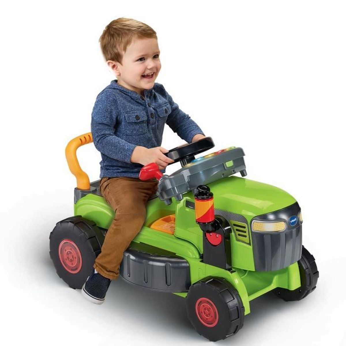Kleinkind sitzt fröhlich auf einem grünen Spielzeugtraktor mit großen schwarzen Rädern.