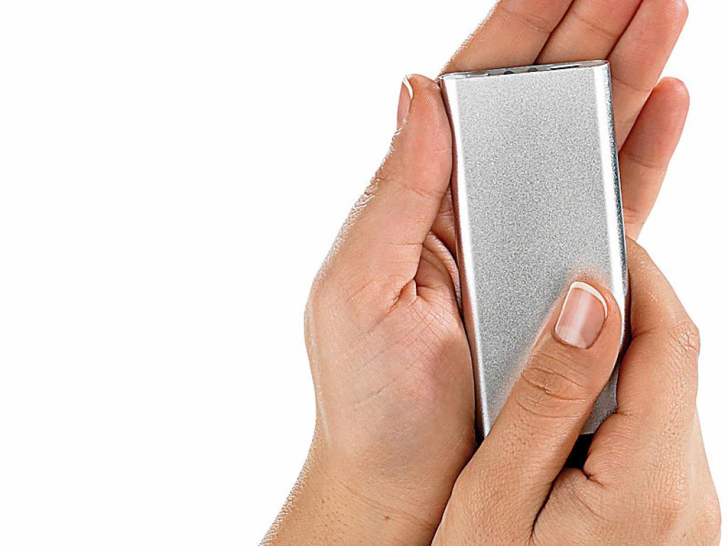 Zwei Hände halten eine silberne Powerbank vor weißem Hintergrund.