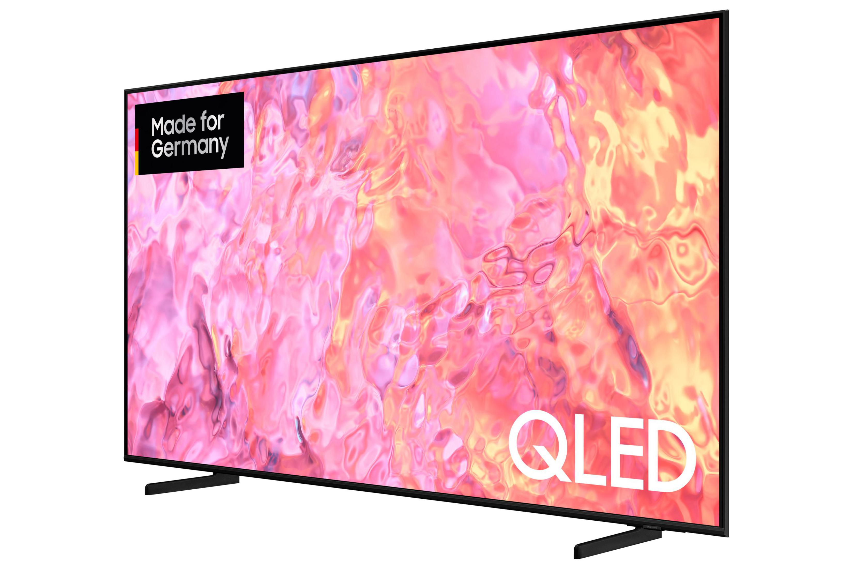 Ein QLED-Fernseher mit pinkem abstrakten Bild und dem Text Made for Germany in der Ecke auf weißem Hintergrund.