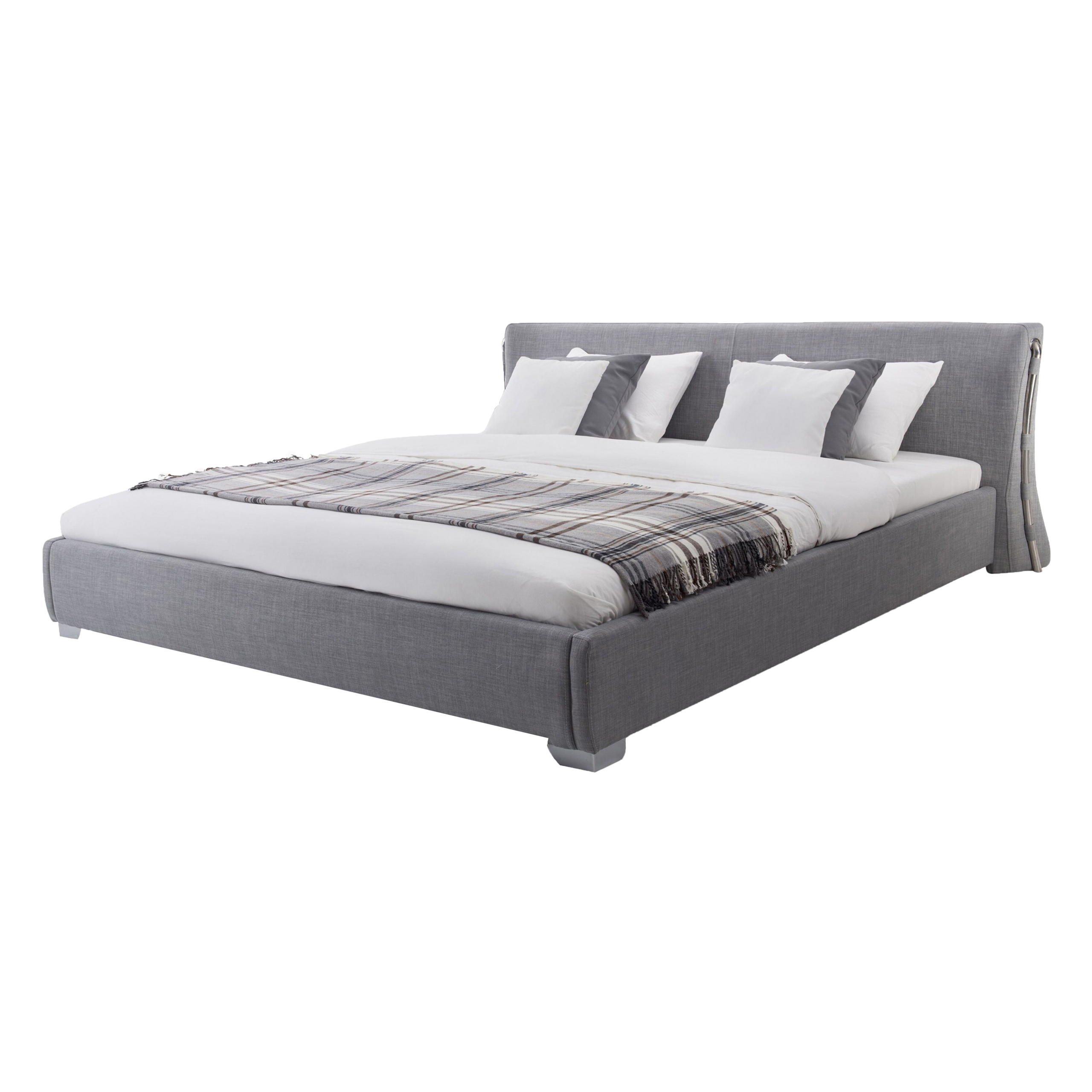 Un letto matrimoniale imbottito grigio con lenzuola bianche, cuscini e una coperta a quadri su sfondo bianco.