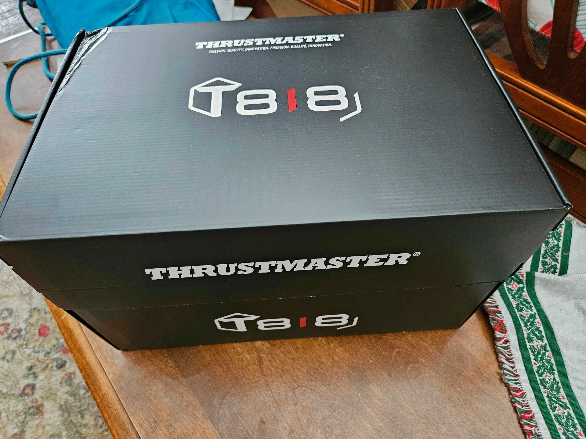 Una caja de producto negra Thrustmaster T818 sobre una superficie de madera.