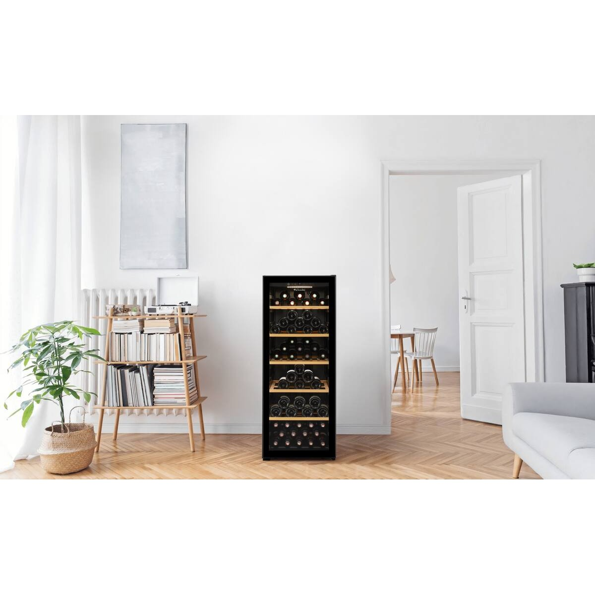 Un enfriador de vino negro se encuentra en una sala de estar luminosa contra una pared blanca.