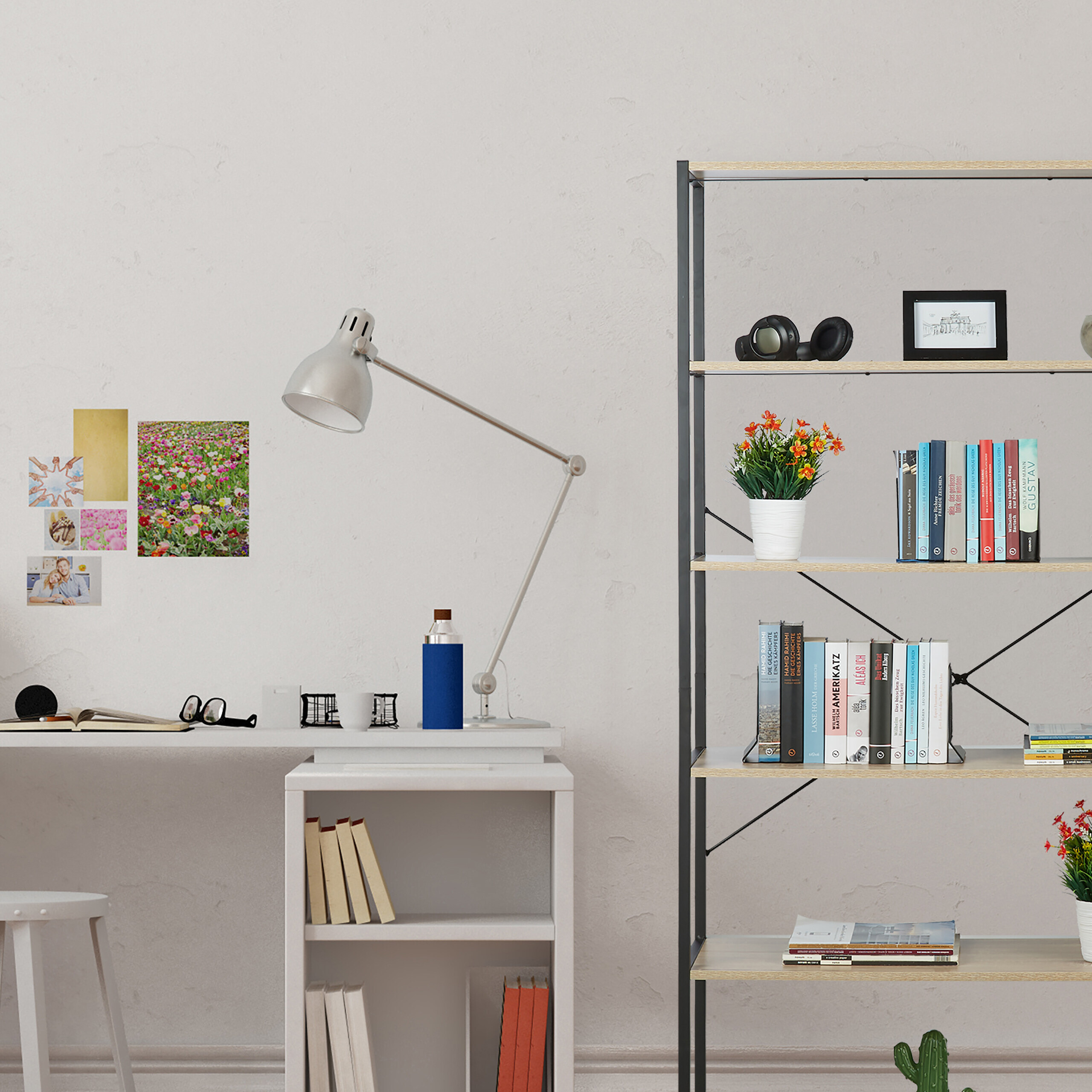 Ein weißer Schreibtisch mit Lampe, Büchern und Postern an der Wand, daneben ein großes Metallregal mit Deko.