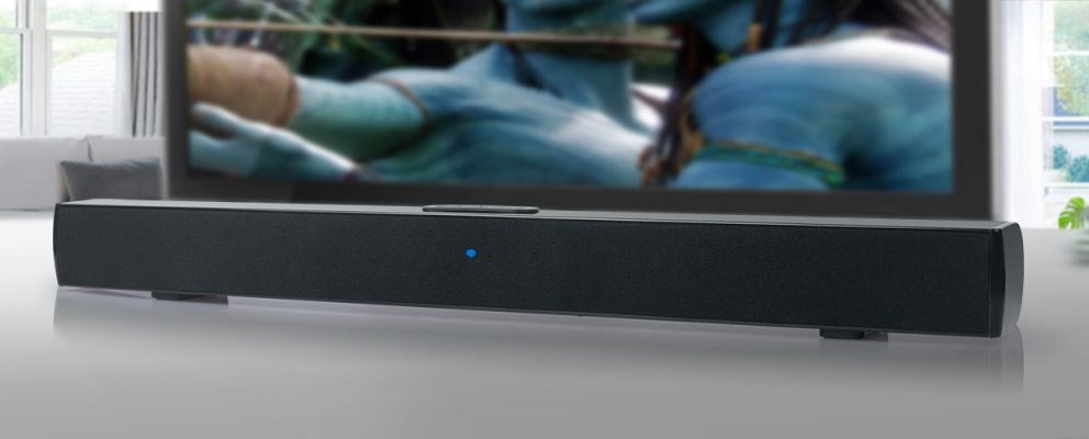 Eine schwarze Soundbar mit blauer Kontrollleuchte steht auf einer weißen Oberfläche unter einem großen Fernseher.