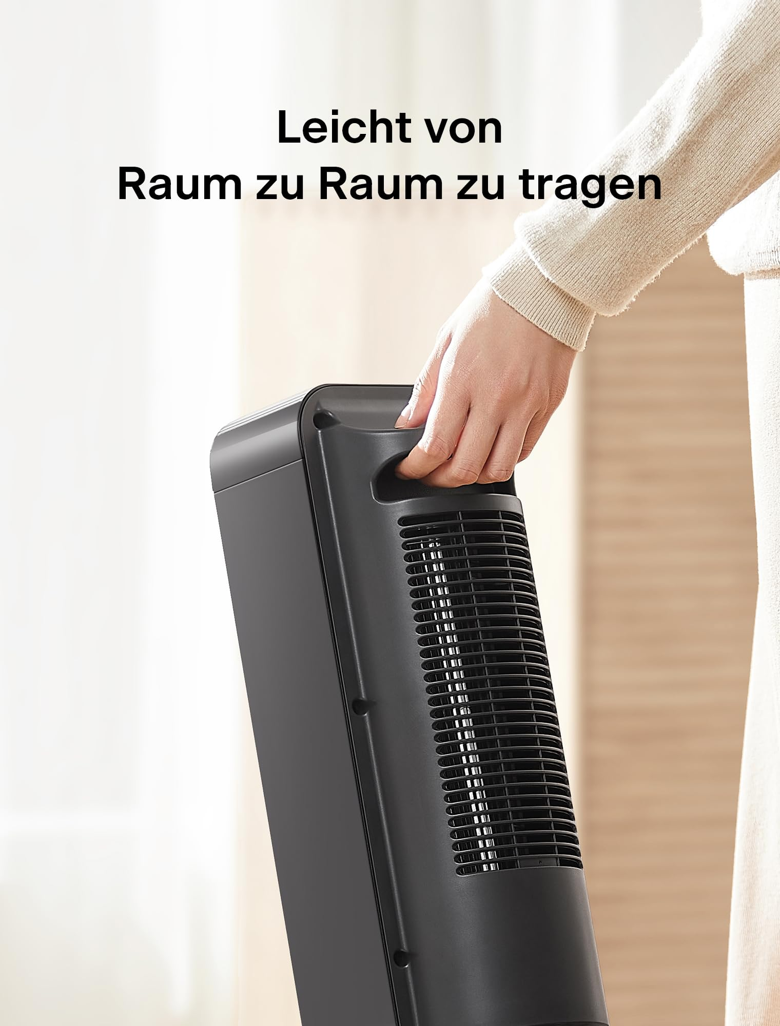 Eine Person trägt einen tragbaren schwarzen Turmventilator mit integriertem Griff.