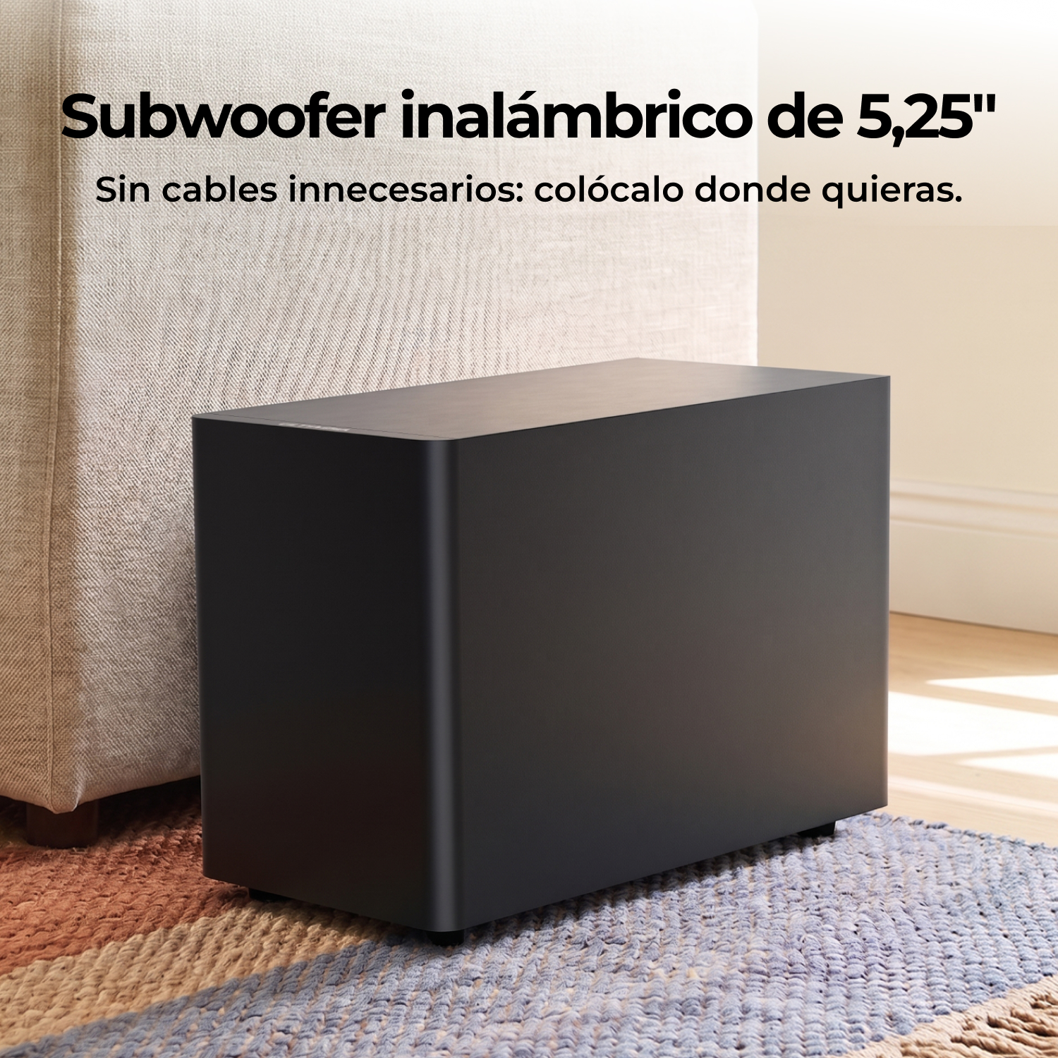 Un subwoofer inalambrico negro descansa sobre una alfombra estampada junto a un sofa beige.