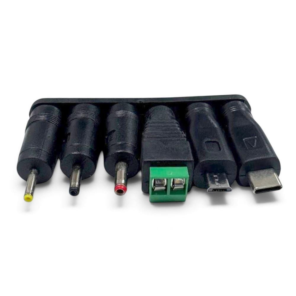 Bir tutucuda altı farklı siyah fiş; varil jakları, vidalı terminaller, micro-USB ve USB-C içerir.