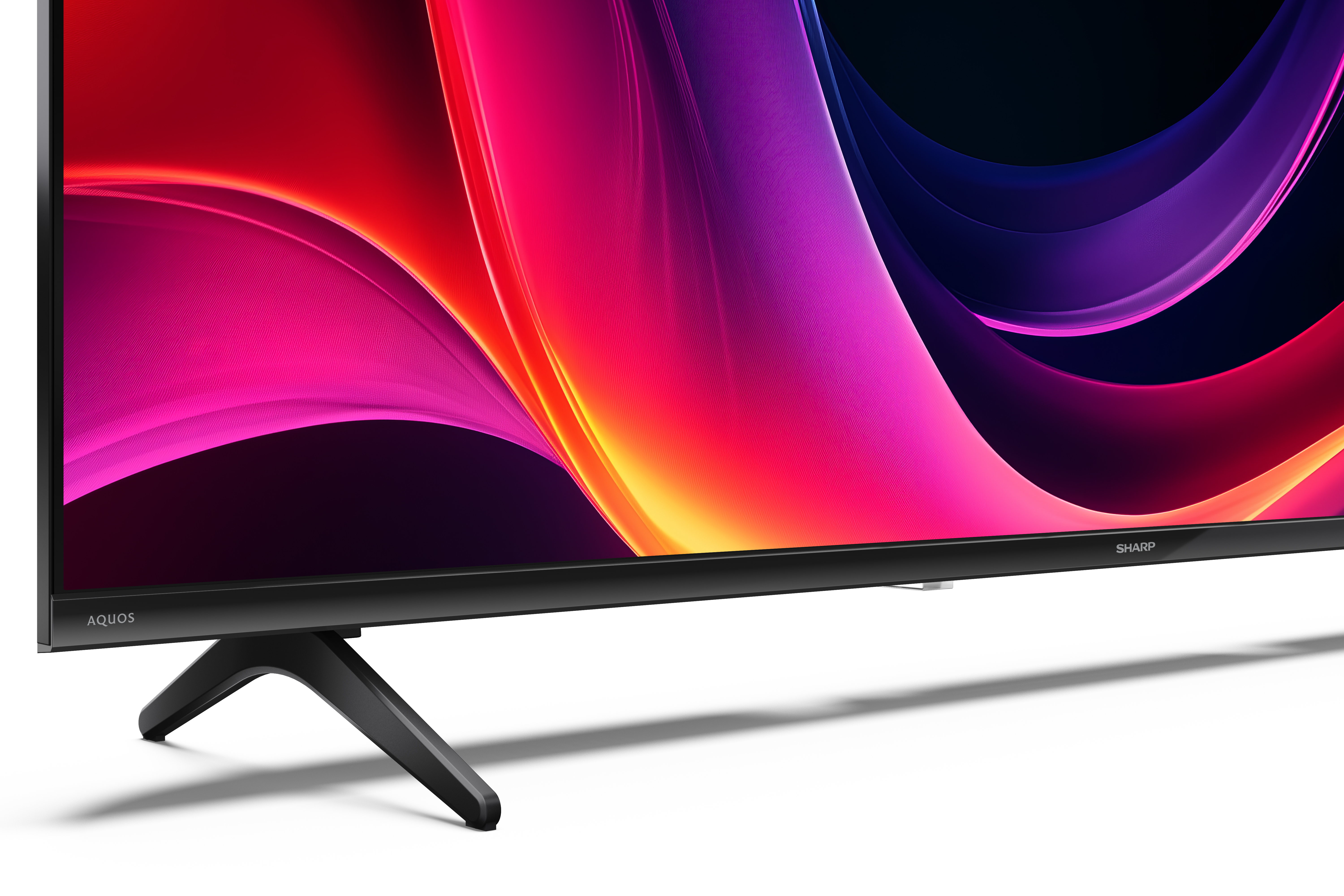 Nowoczesny telewizor z czarną ramką i podstawką wyświetla kolorowy abstrakcyjny obraz.
