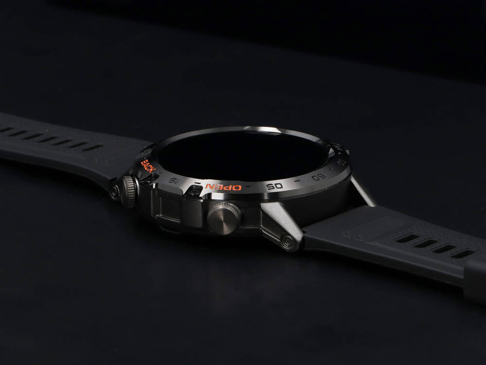Czarny smartwatch z wytrzymałą metalową kopertą i ciemnym paskiem silikonowym na ciemnym tle.
