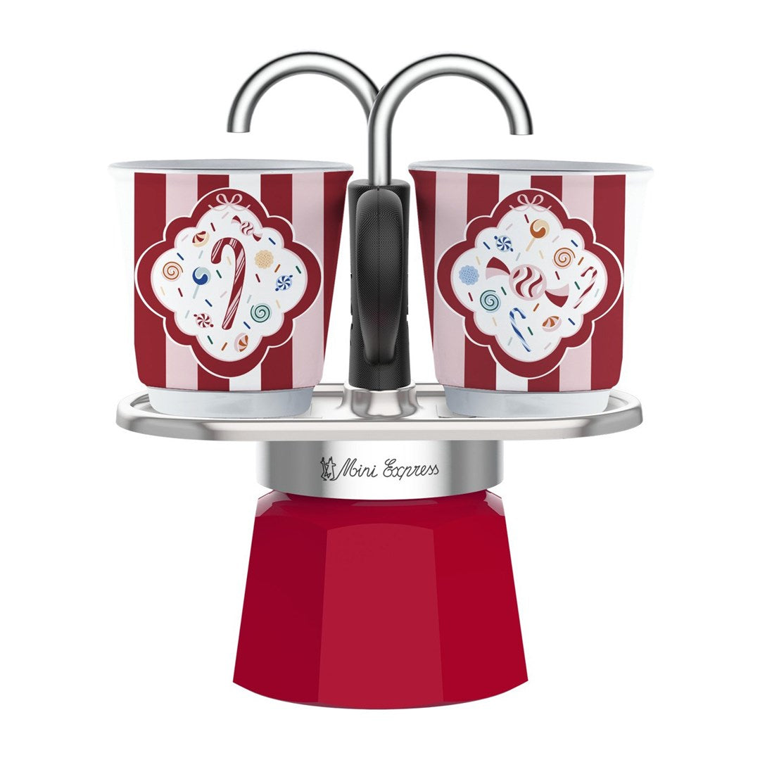 Una caffettiera rossa Mini Express con due tazze natalizie a righe su un vassoio argentato.