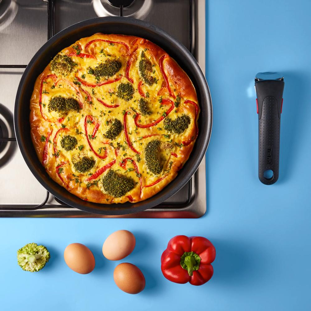 Frittata z brokułami i czerwoną papryką na patelni na kuchence.