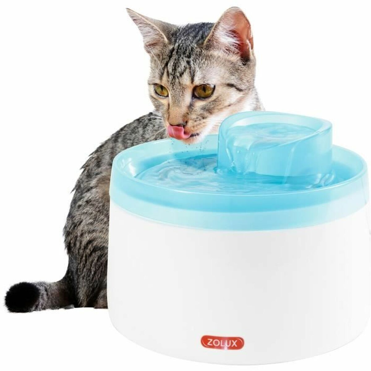 Eine gestreifte Katze leckt ihre Nase, während sie aus einem weiß-hellblauen Trinkbrunnen trinkt, vor weißem Hintergrund.
