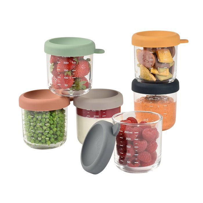 Fünf Glasbehälter mit farbigen Silikondeckeln gefüllt mit Erdbeeren, Erbsen, Snacks, Joghurt und Himbeeren.