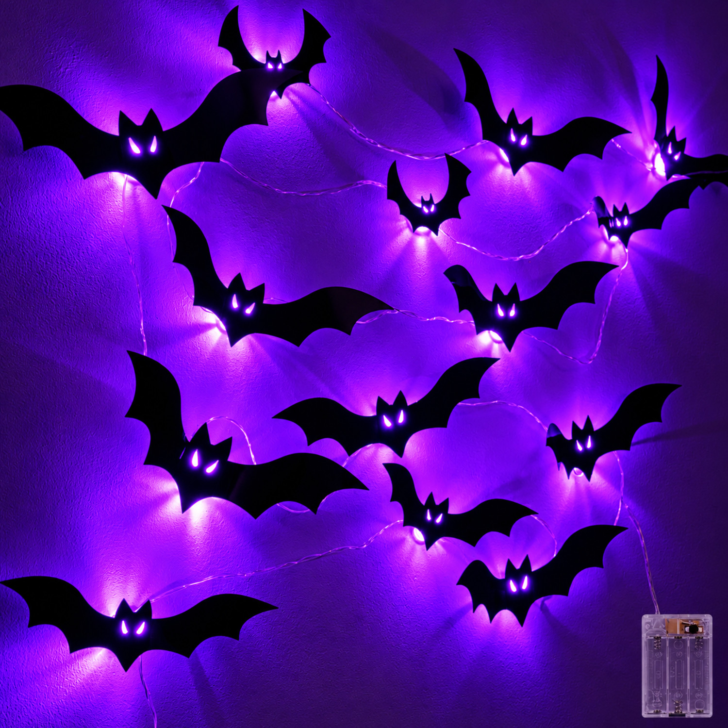 Lichterkette mit schwarzen Fledermäusen und leuchtend lila Augen an einer lila Wand.
