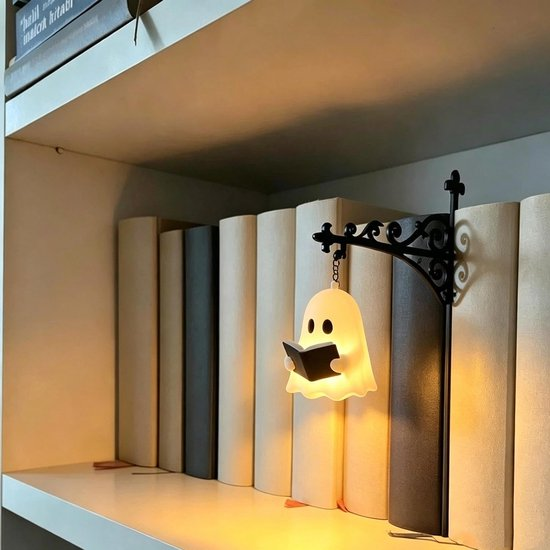 Eine kleine Geist-Lampe liest ein Buch, hängend an einem schwarzen Halter zwischen vielen Büchern im Regal.