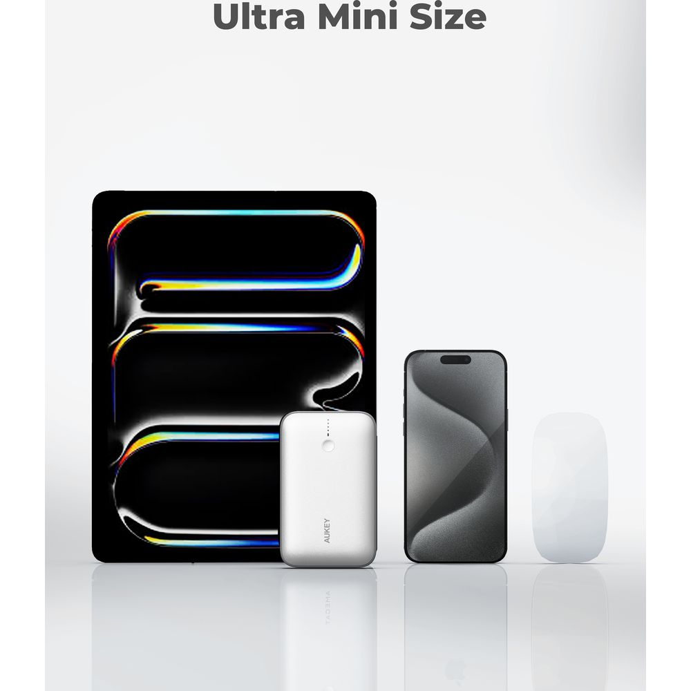 Ultra mini boyutlu taşınabilir şarj cihazı, açık gri yansıtıcı yüzeyde tablet, akıllı telefon ve beyaz fare yanında duruyor.