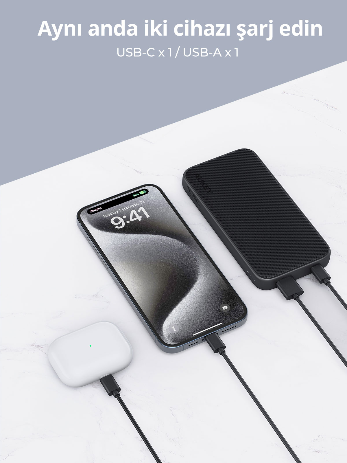 Bir taşınmaz şarj cihazı, açık renkli masada telefon ve kulaklık şarj ediyor.