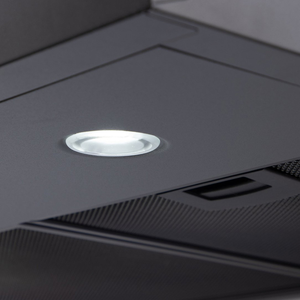 A close-up of a modern dark grey cooker hood with a single glowing round white LED spotlight on its flat surface.